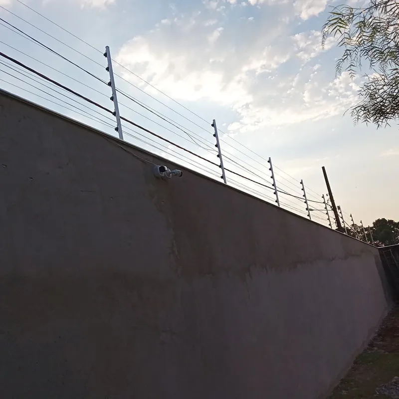 Muro com cerca elétrica no topo e câmera de segurança fixada na lateral