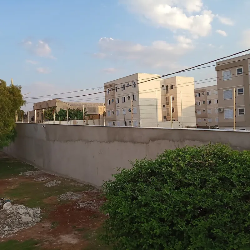 Muro de terreno com cerca elétrica instalada e prédios de um condomínio ao fundo