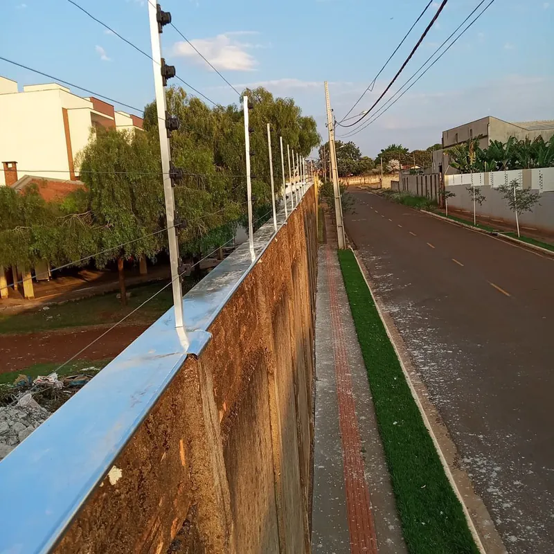 Muro alto de divisa com cerca elétrica instalada sobre rufo metálico, ao lado da rua